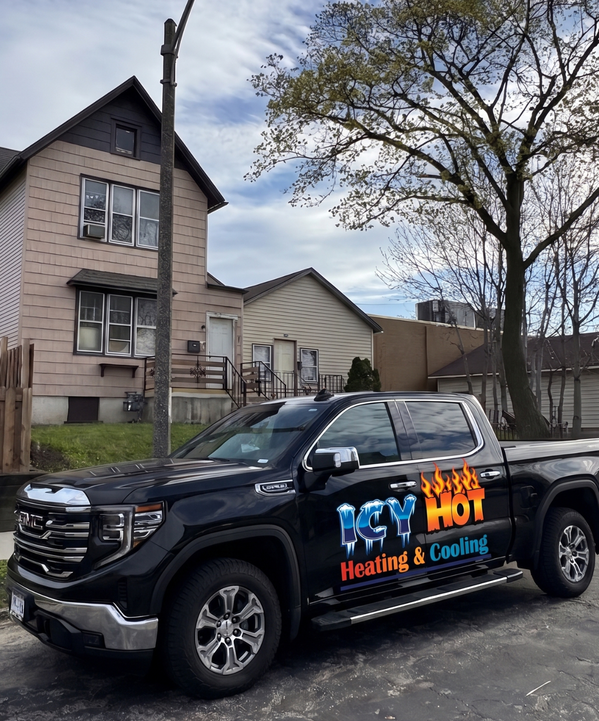 Black Icy Hot Heating and Cooling pickup truck with the flame and ice door logo, parked on a Milwaukee street