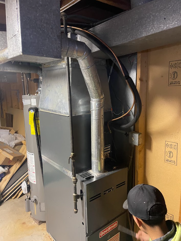 Technician finishing a Goodman furnace install in a basement