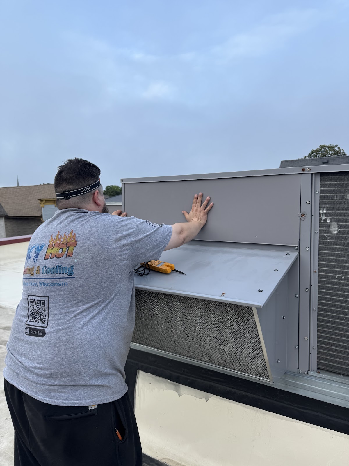 Icy Hot technician fitting a panel on a commercial rooftop unit