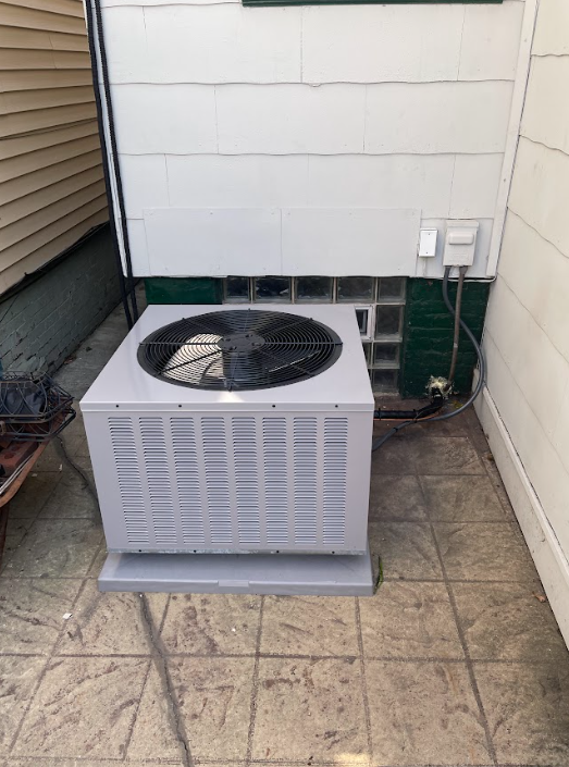 New AC condenser set on a pad beside a house