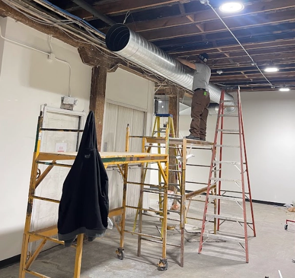 Technician on a scaffold hanging spiral duct in an open ceiling